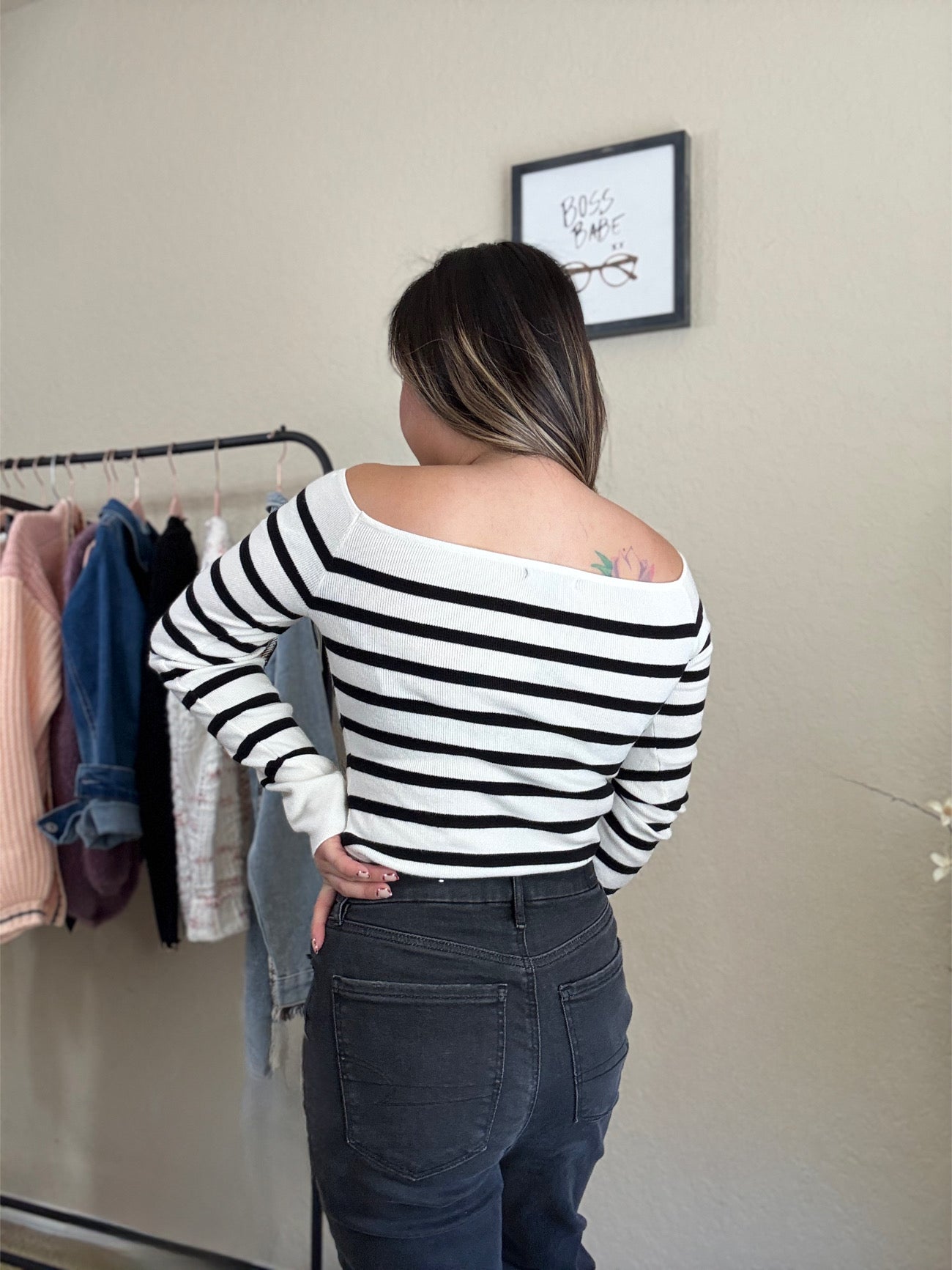 back view of a model in black and white striped off-shoulder sweater with a classic knit design.