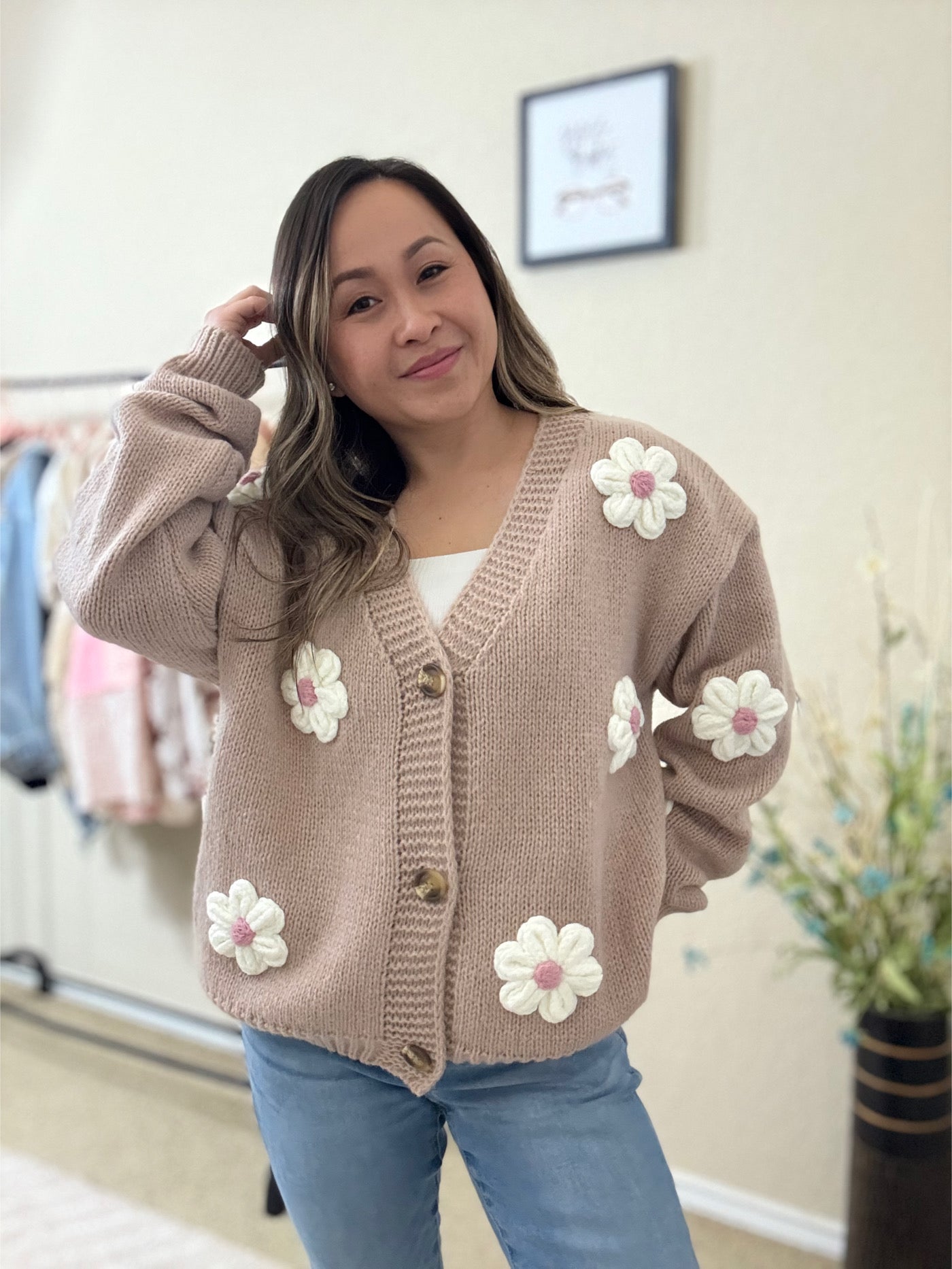 Front view of the Lili Flower Cardigan, a beige knit sweater made from 100% polyester, featuring white 3D floral appliqués and a relaxed fit