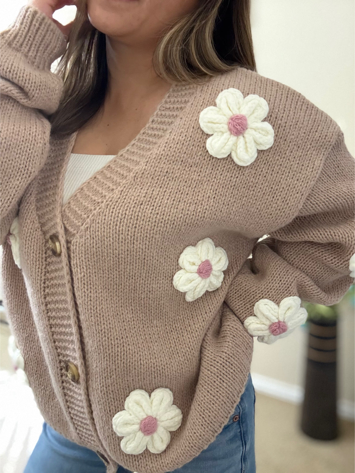 side view of the Lili Flower Cardigan, a beige knit sweater made from 100% polyester, featuring white 3D floral appliqués and a relaxed fit