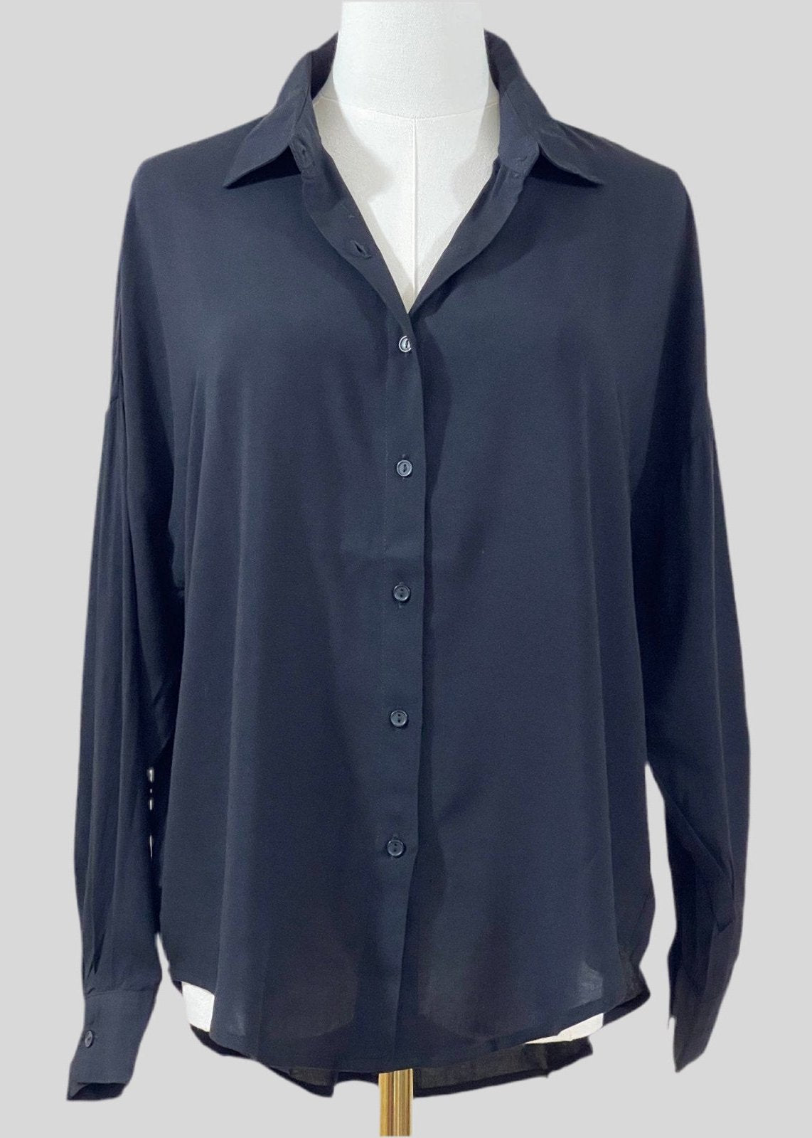 Front view of a black oversized button-down shirt featuring a relaxed fit and lightweight fabric.