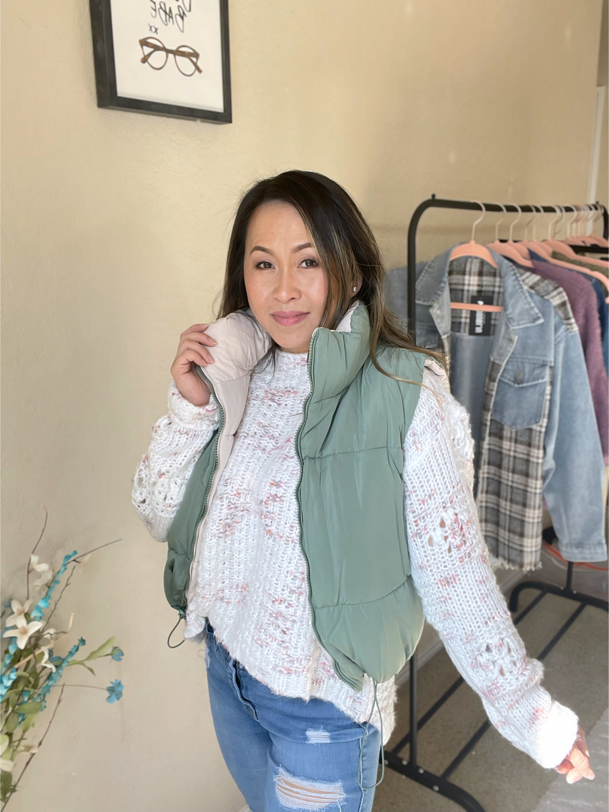 Woman wearing a reversible woven vest paired with a sweater and ripped jeans, styled with casual elegance.