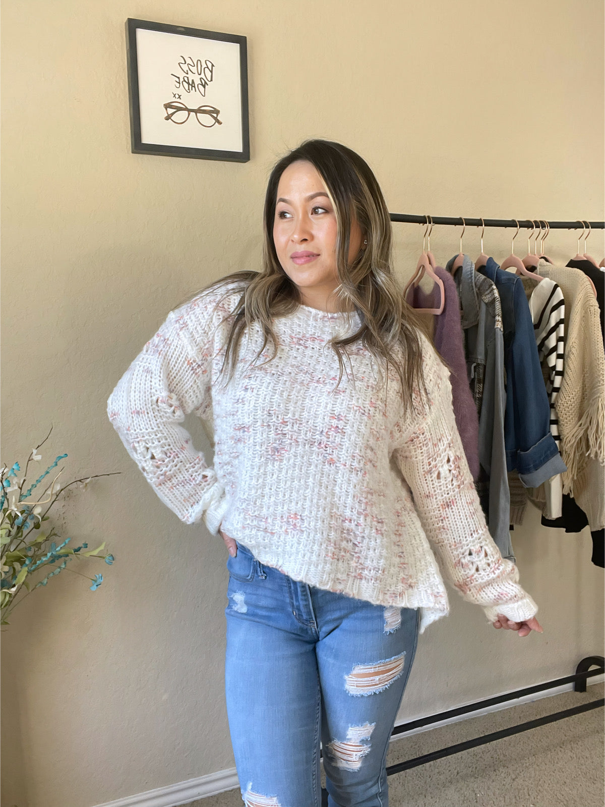 Woman wearing a speckled knit sweater in pink and cream tones, paired with distressed jeans for a casual and stylish outfit.